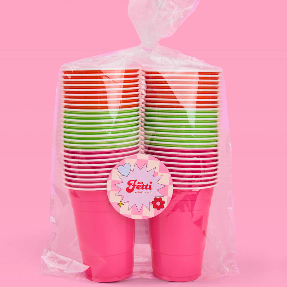 Packaged colorful plastic cups with a pink background