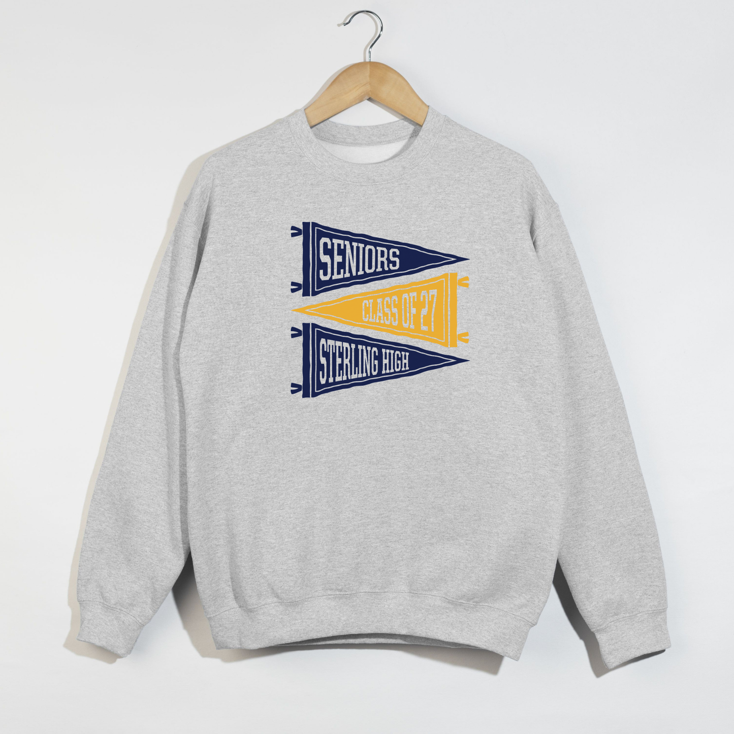 Light blue Sterling High Seniors Class of 2027 sweatshirt featuring navy and gold varsity pennant graphics for Sterling Warriors senior spirit wear.