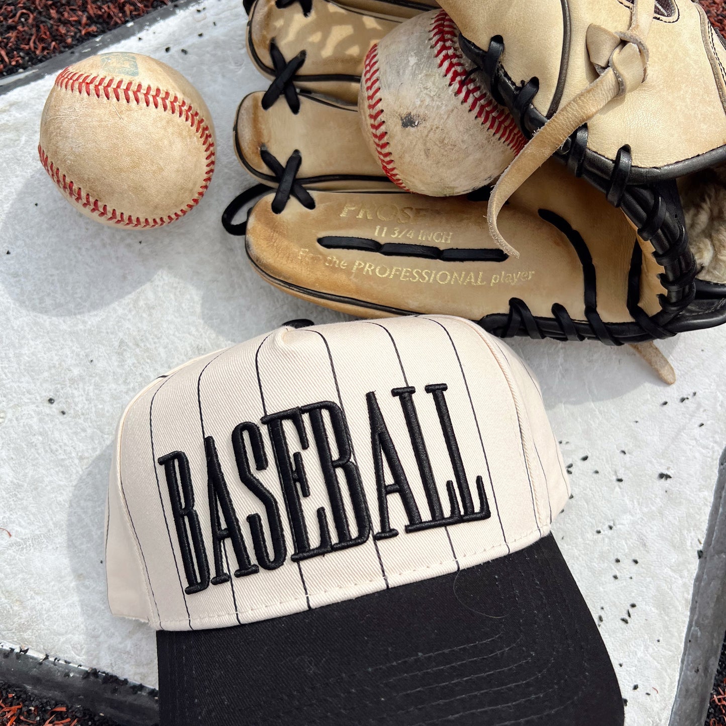 Baseball cap with 'BASEBALL' text, baseball, and glove on a textured surface