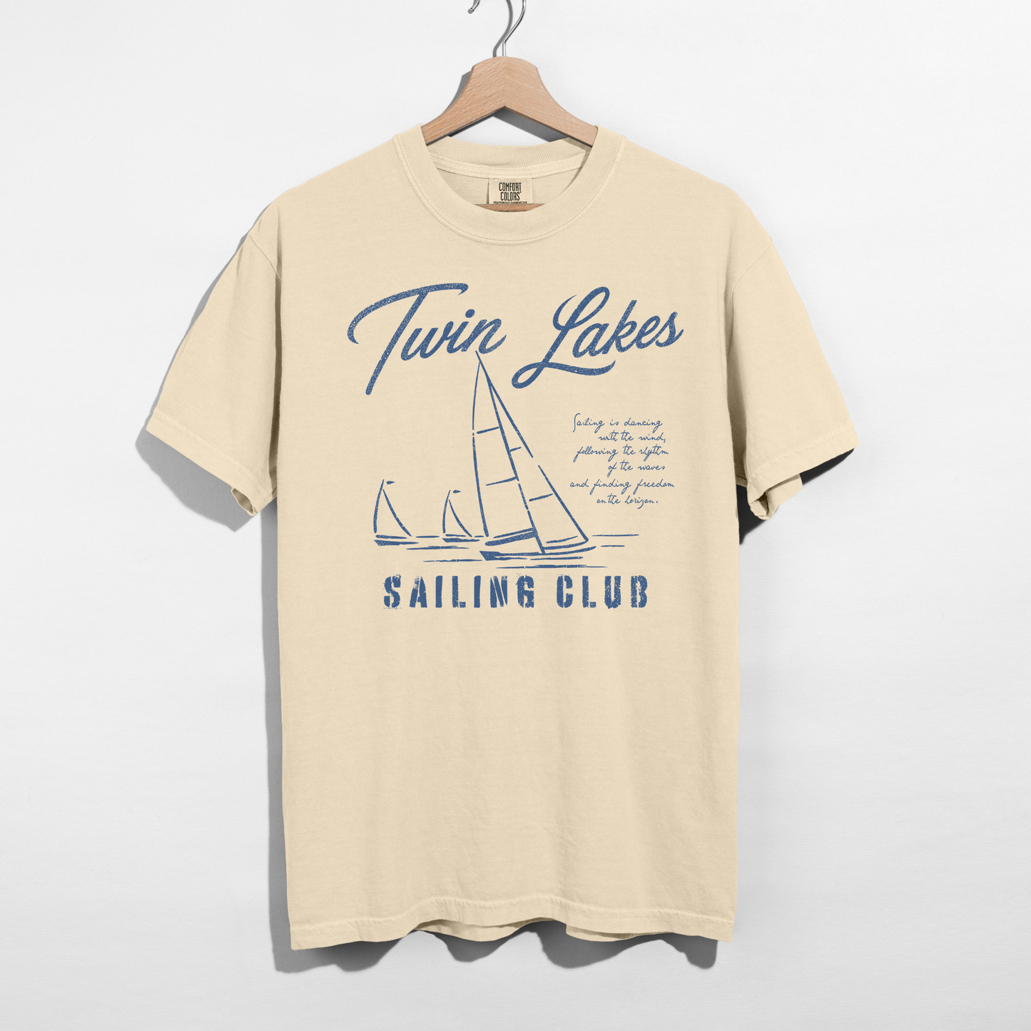 Twin Lakes Sailing Club graphic tee featuring vintage sailboat artwork and distressed navy blue nautical design on a cream Comfort Colors shirt.