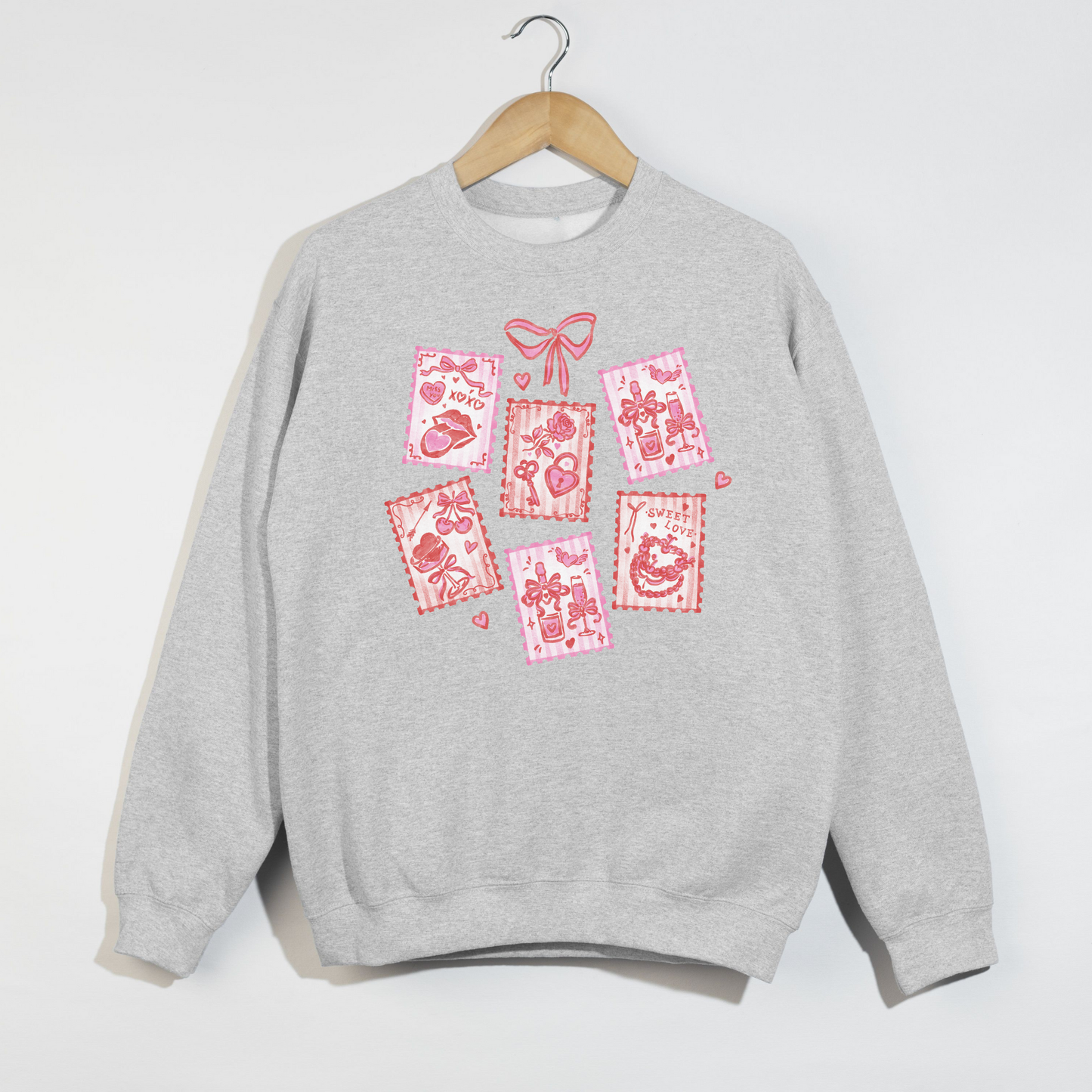 Ash grey sweatshirt on hanger featuring pink and red Valentine stamp illustrations.