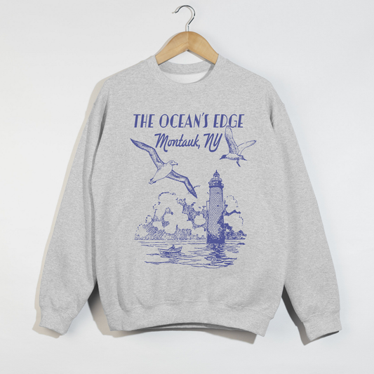 "Ash grey sweatshirt with blue Montauk lighthouse and seagulls coastal design displayed on hanger."