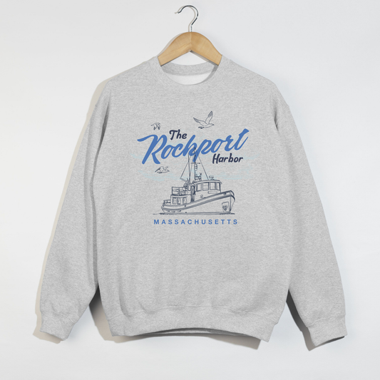 Gray sweatshirt with 'The Rockport Harbor, Massachusetts' design on a hanger against a white background