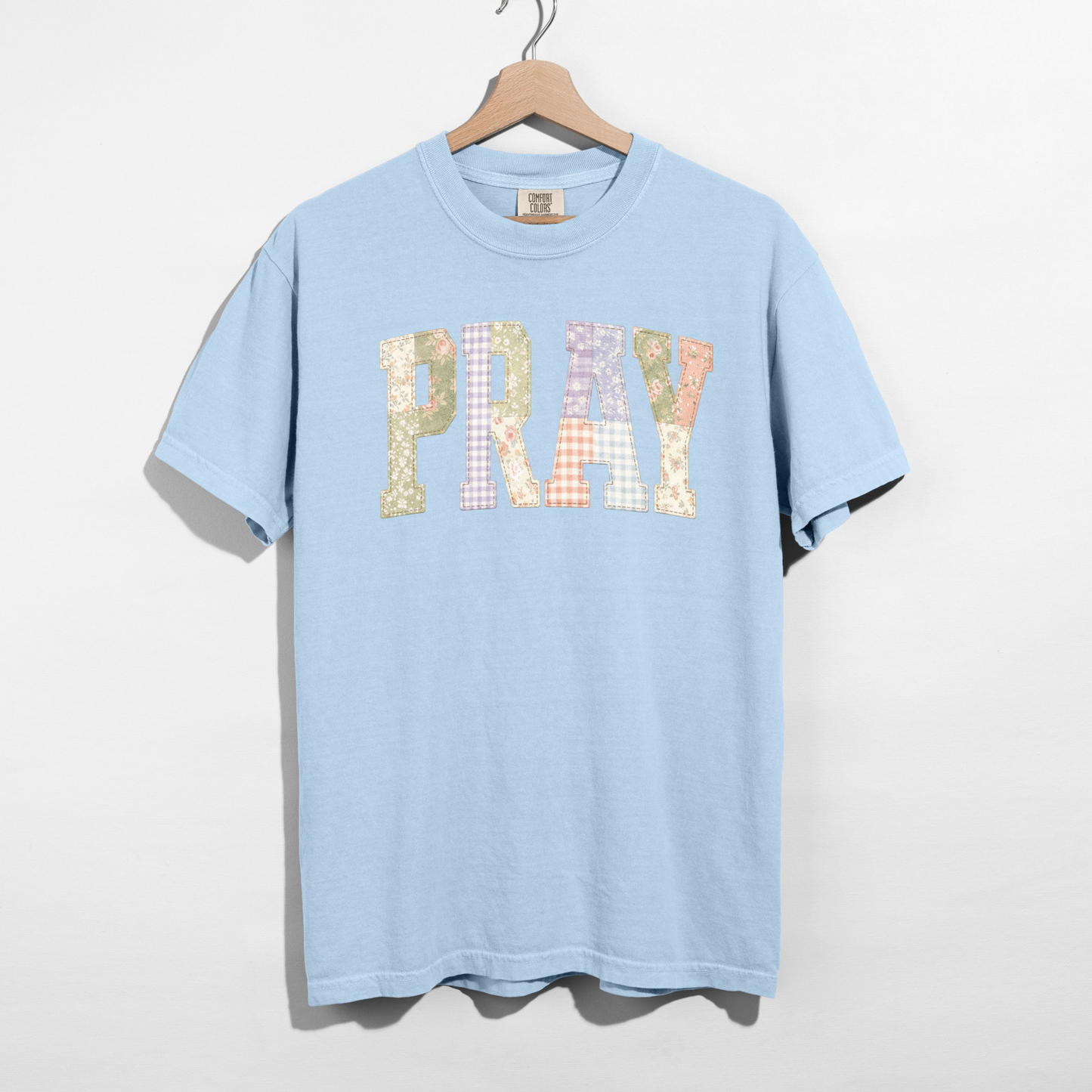 Light blue Comfort Colors PRAY faux patchwork graphic t-shirt on hanger