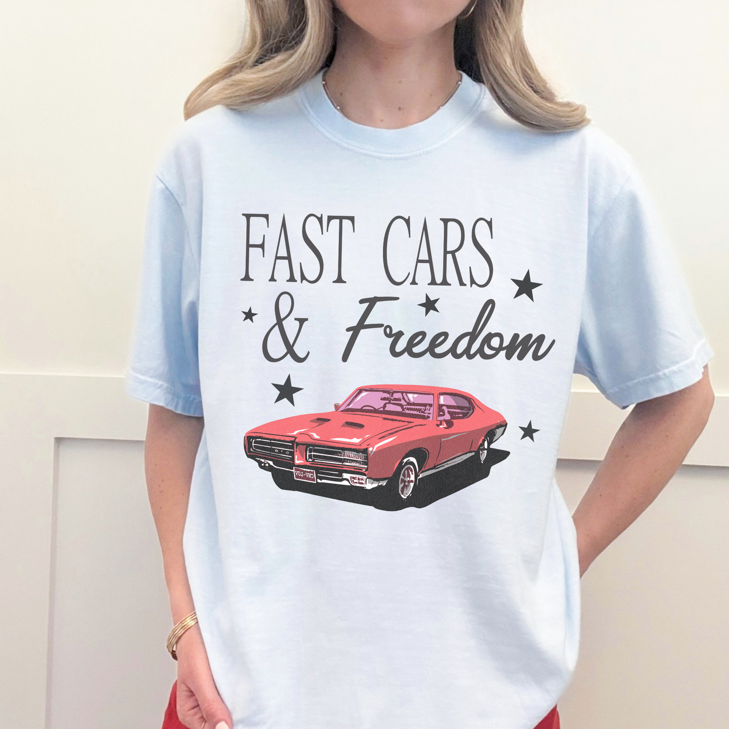 Chambray blue Fast Cars & Freedom t-shirt with retro red muscle car graphic and black star accents styled casually.