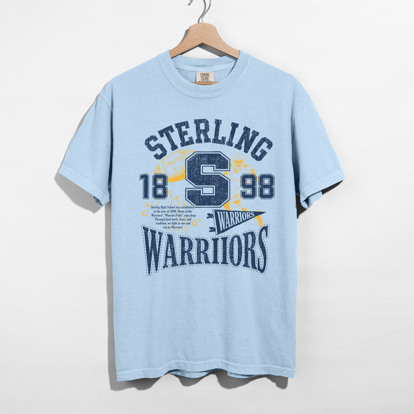 Chambray blue Sterling Warriors Football graphic tee with distressed varsity lettering, football artwork, and classic navy and gold school spirit design.