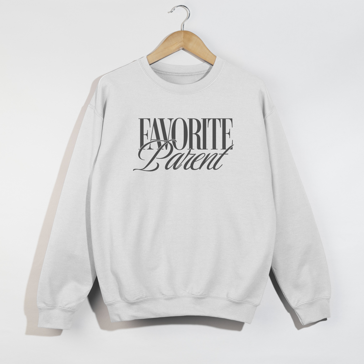 White Favorite Parent crewneck sweatshirt with bold black graphic print hanging on wooden hanger