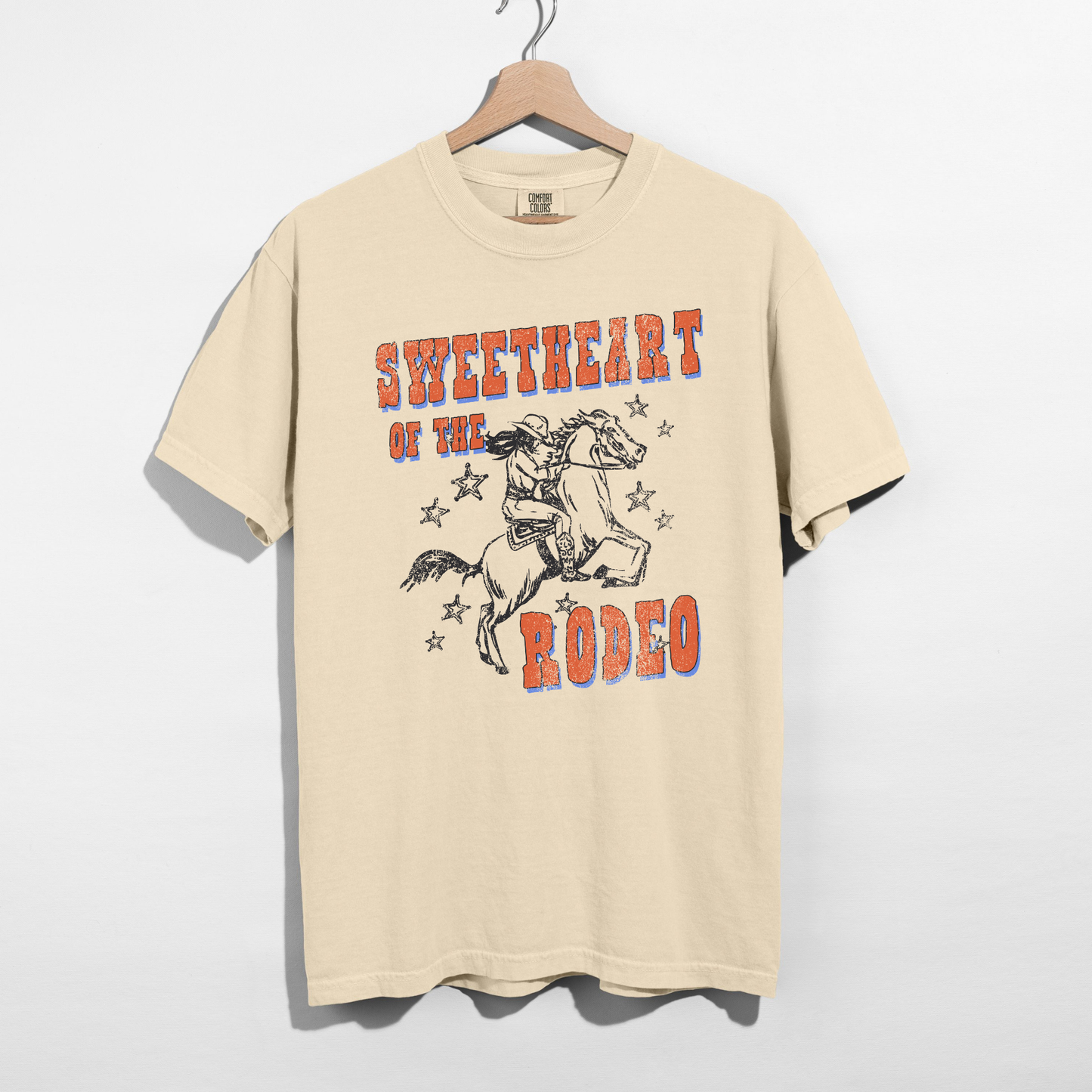 Ivory comfort colors t-shirt with sweetheart of the rodeo western horse graphic hanging on hanger