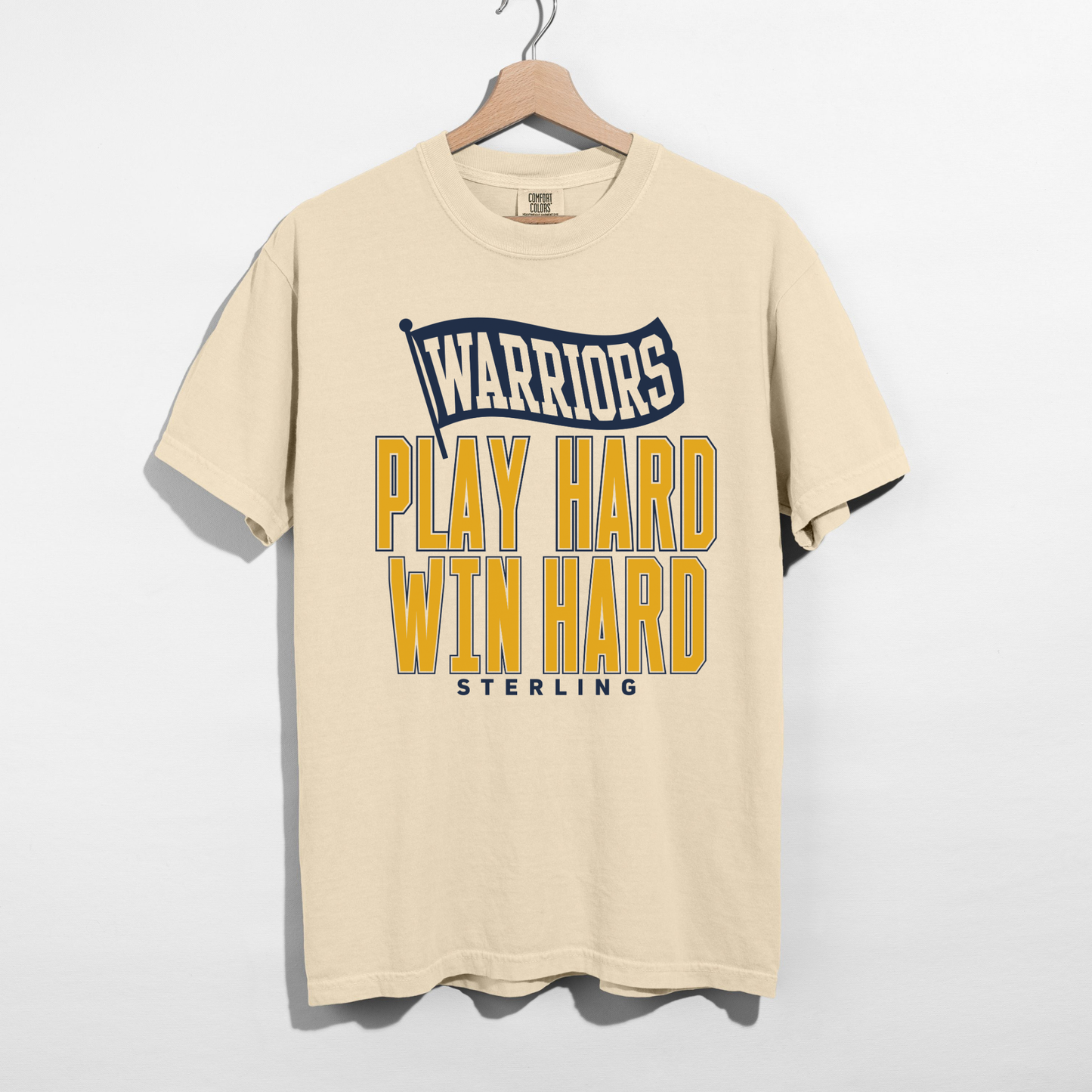 Ivory Comfort Colors Sterling Warriors Play Hard Win Hard varsity graphic t-shirt featuring navy flag design and bold gold lettering.