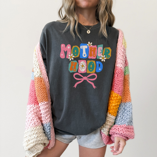 “Dark grey Motherhood tee featuring colorful retro letters and bow design.”