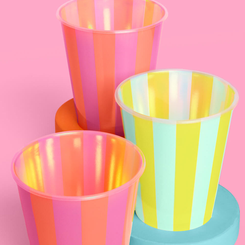 Three colorful striped cups on a pink background