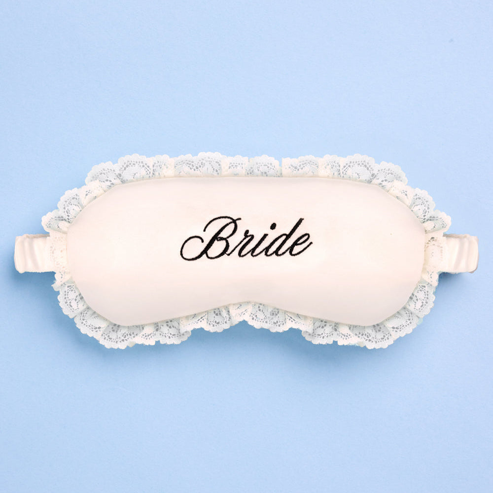 Sleep mask with lace trim and 'Bride' text on a light blue background