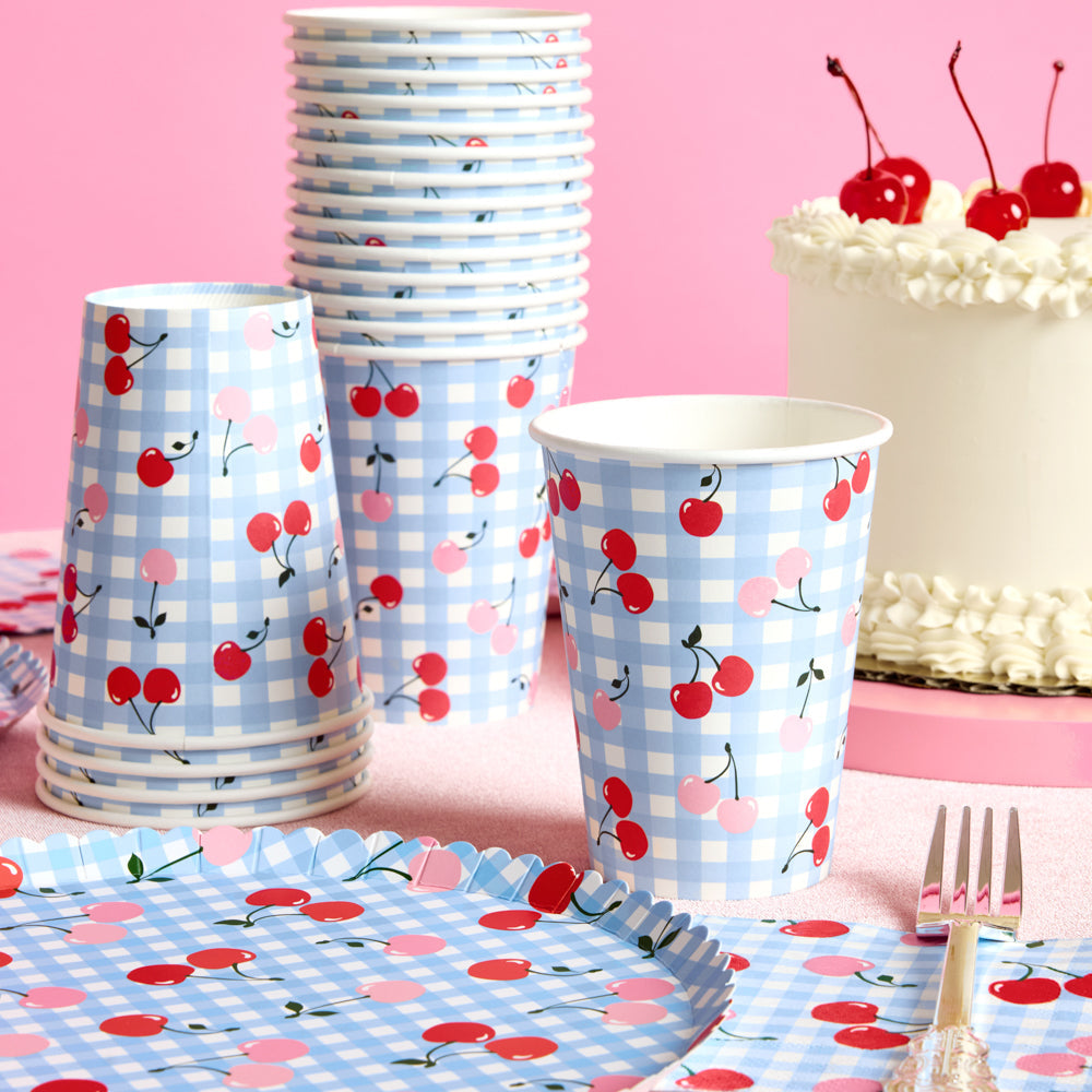 Party supplies with cherry and checkered design on a pink background