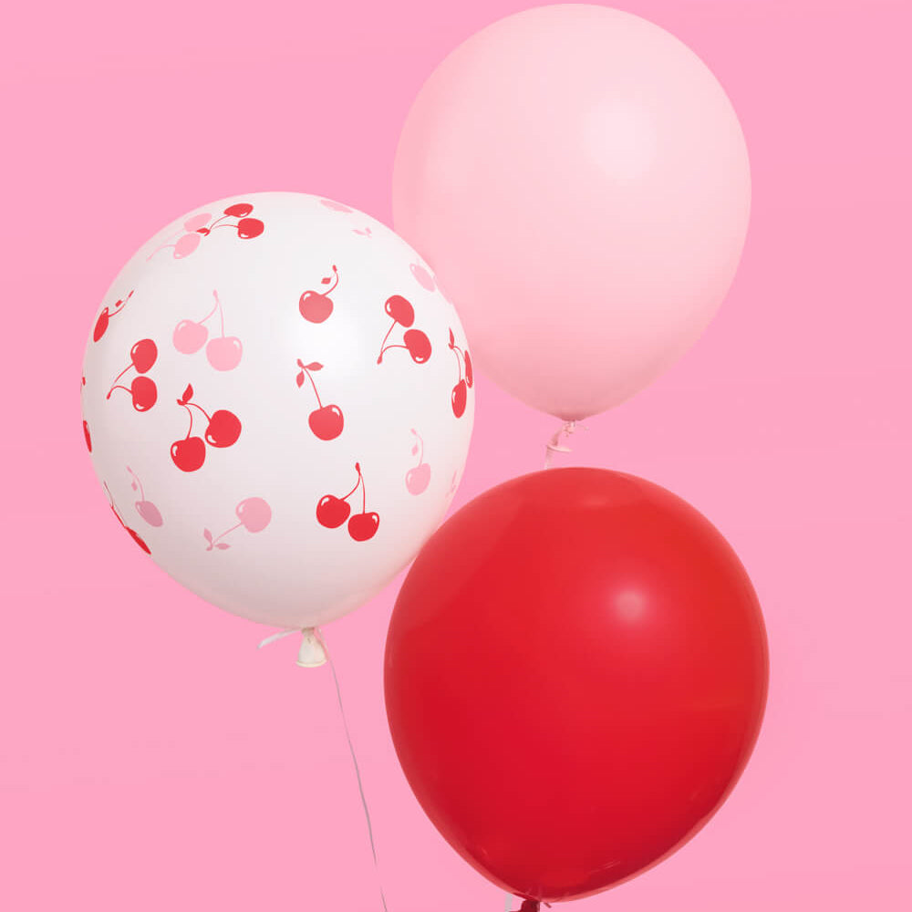 Three balloons with different designs on a pink background