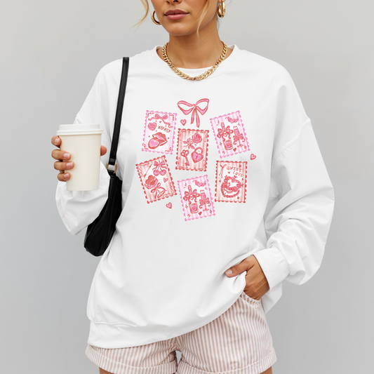 Woman wearing white Valentine stamps sweatshirt with pink hand-drawn graphic, holding coffee.