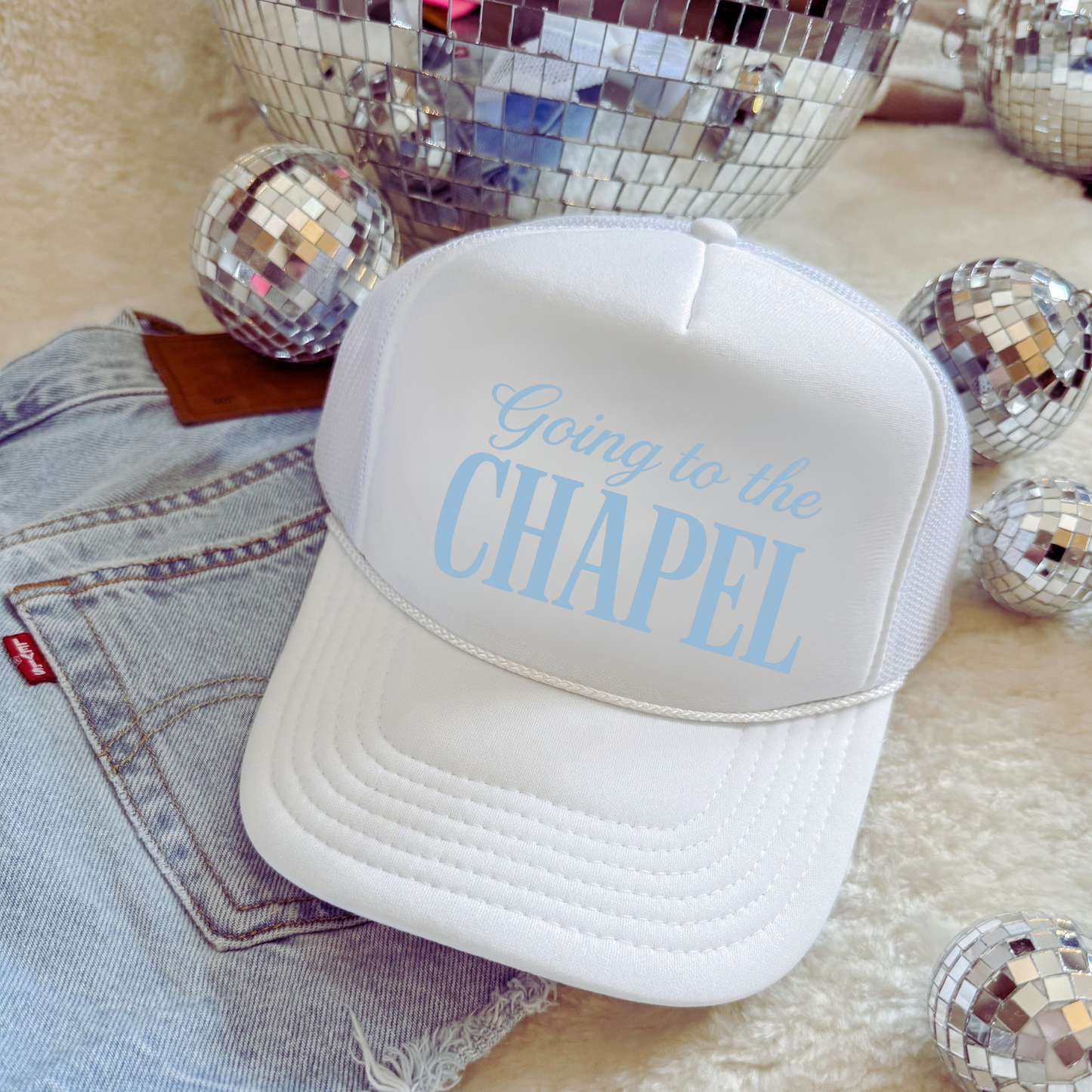 White Going to the Chapel foam front trucker hat with light blue lettering styled with denim and disco balls
