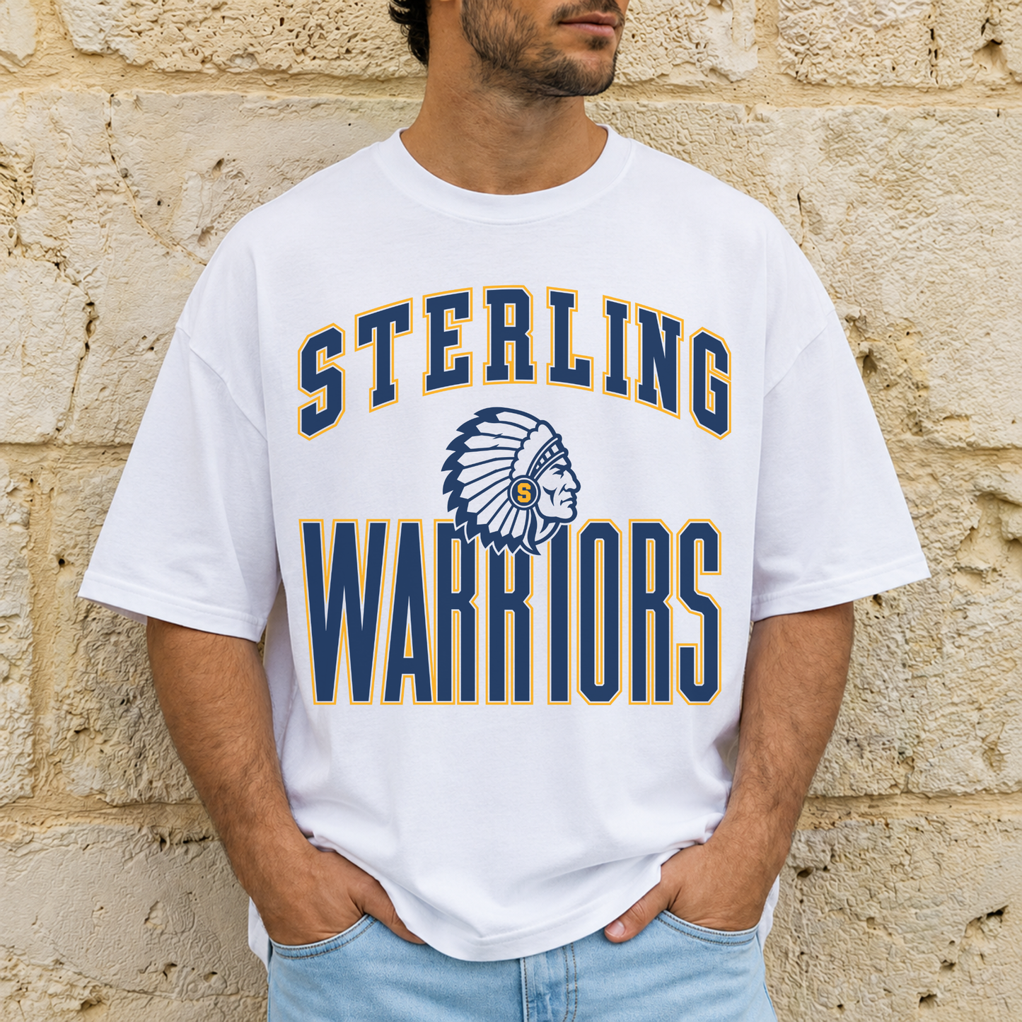 Man wearing a white Sterling Warriors mascot graphic t-shirt featuring vintage collegiate lettering and navy and gold mascot design.