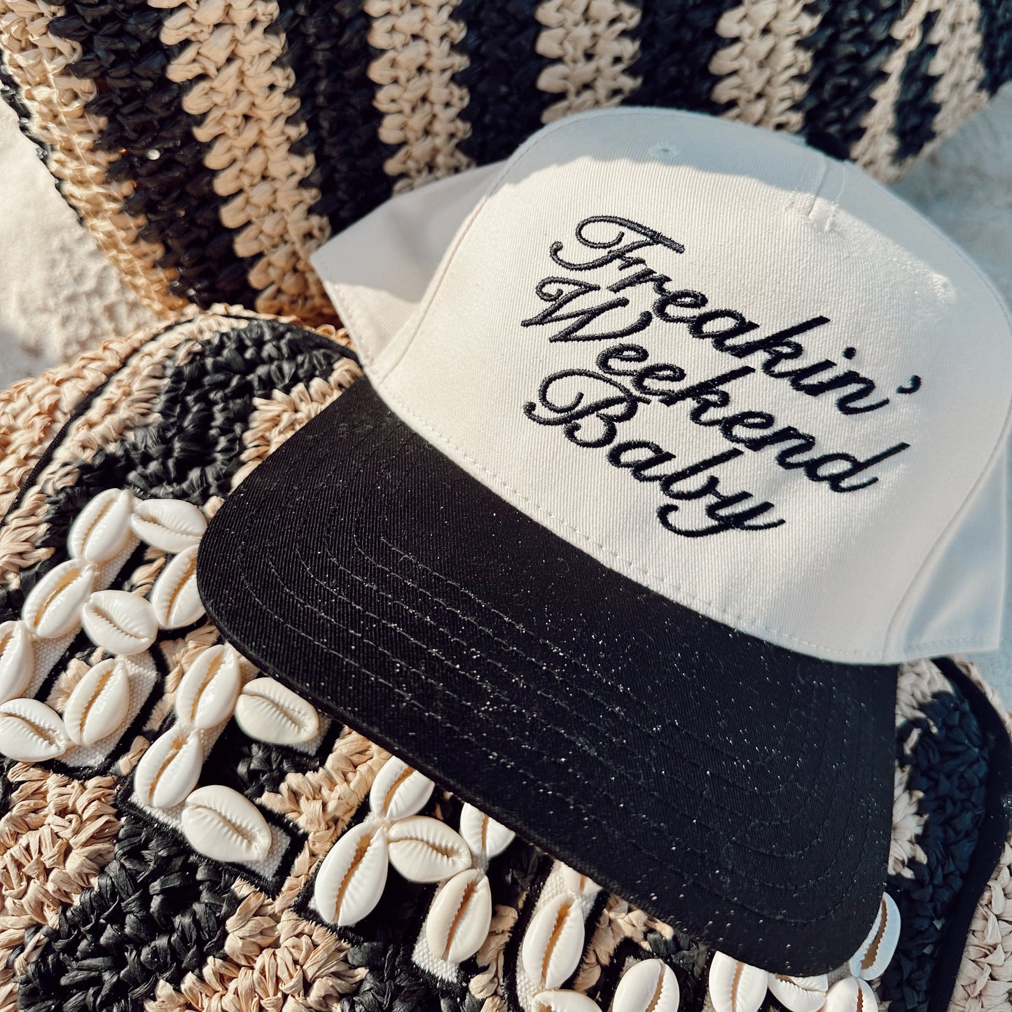 Black and white cap with 'Freakin' Weekend Baby' text on a textured surface