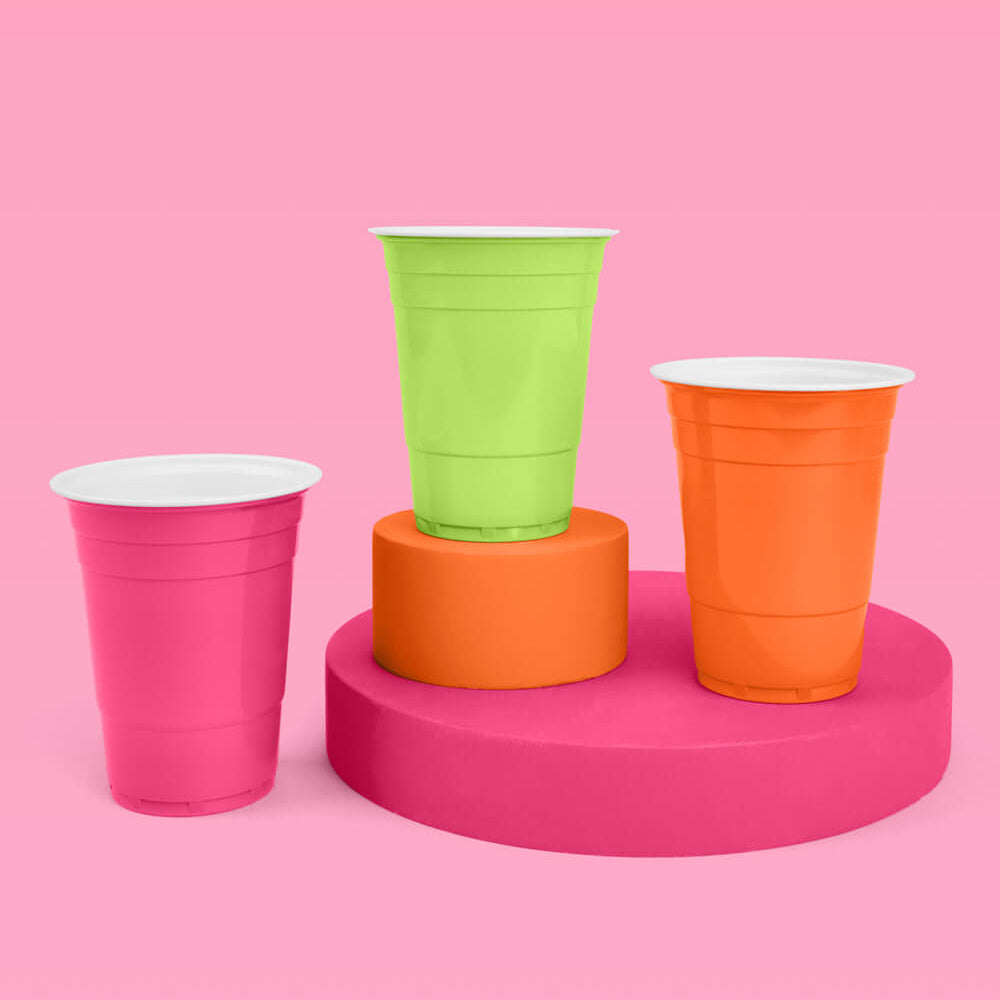 Three colorful plastic cups on a pink platform against a pink background