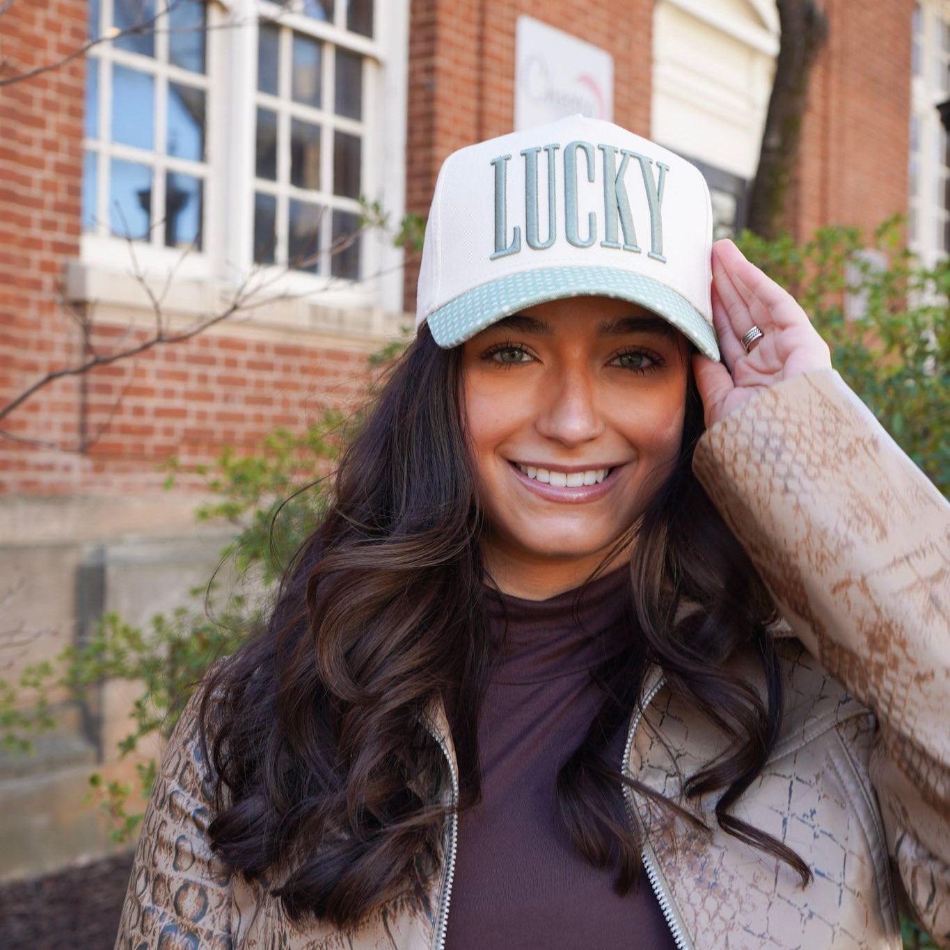 Woman wearing a cap with 'LUCKY' text outdoors