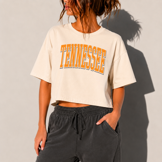Woman wearing an ivory boxy cropped Tennessee graphic t-shirt with vintage collegiate orange lettering paired with charcoal lounge pants.