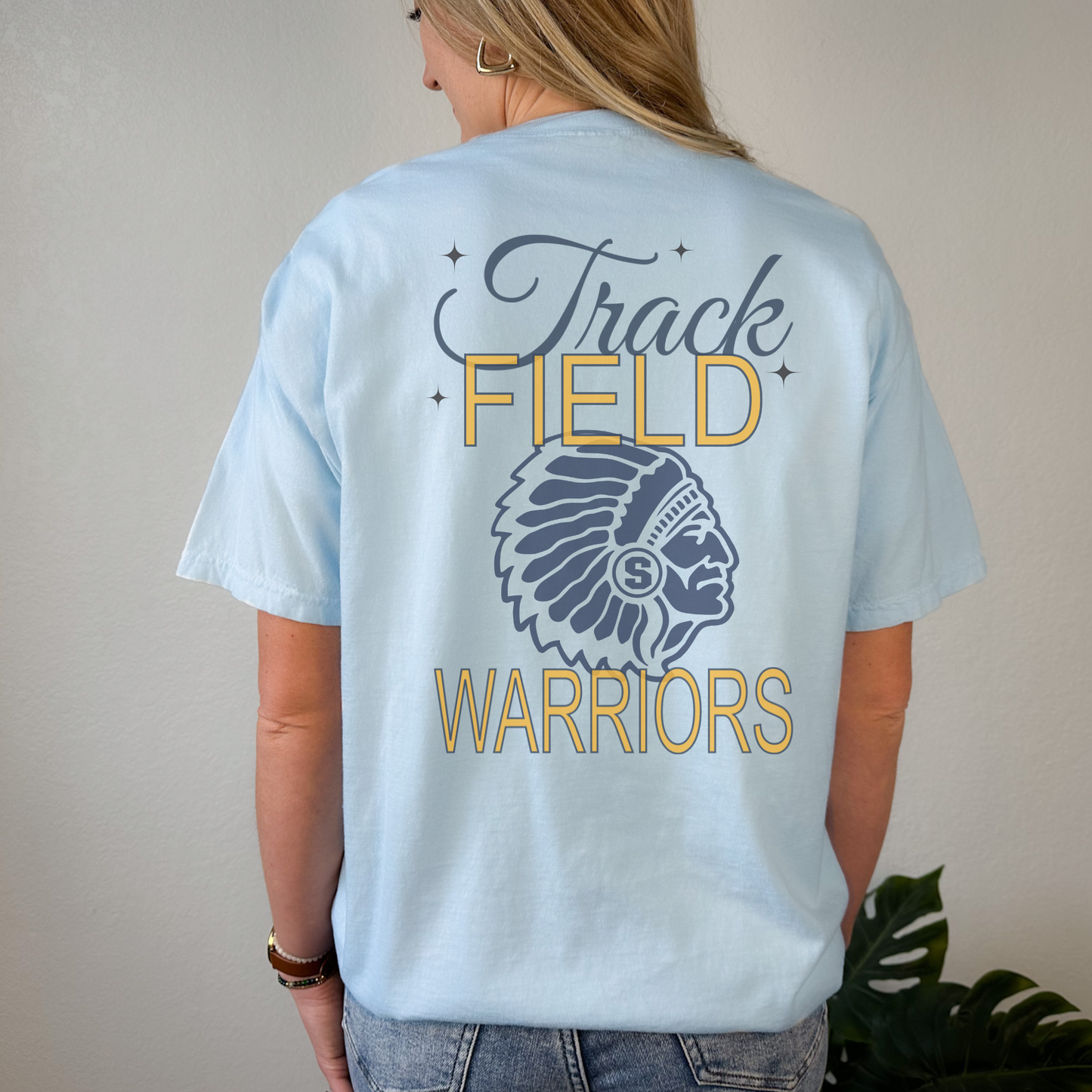 Light blue t-shirt with 'Track Field Warriors' design on the back, worn by a person.