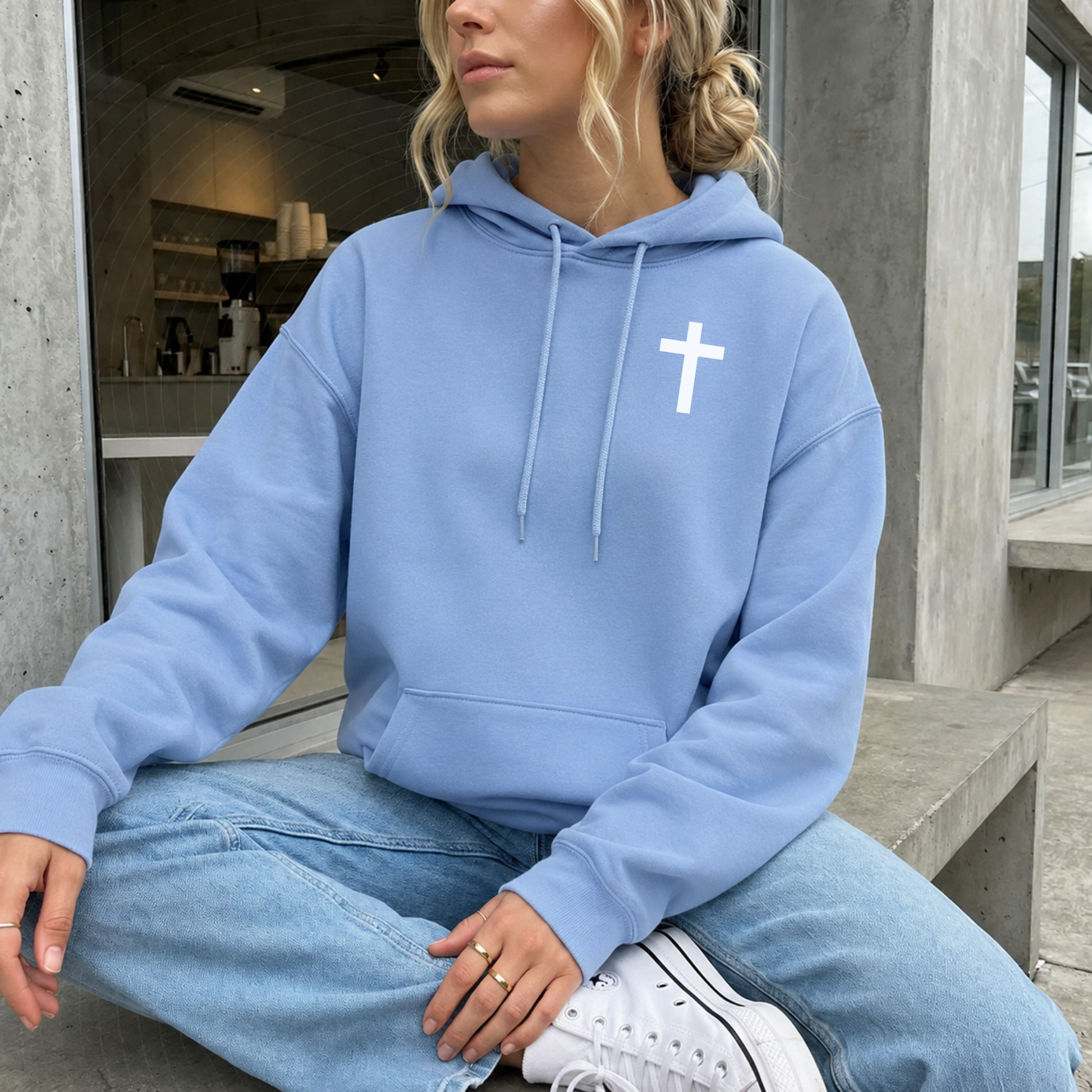 Lifestyle model wearing colony blue Christian hoodie with white cross chest design.