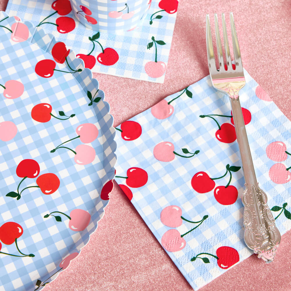 Napkins with cherry pattern on a pink surface with a fork.