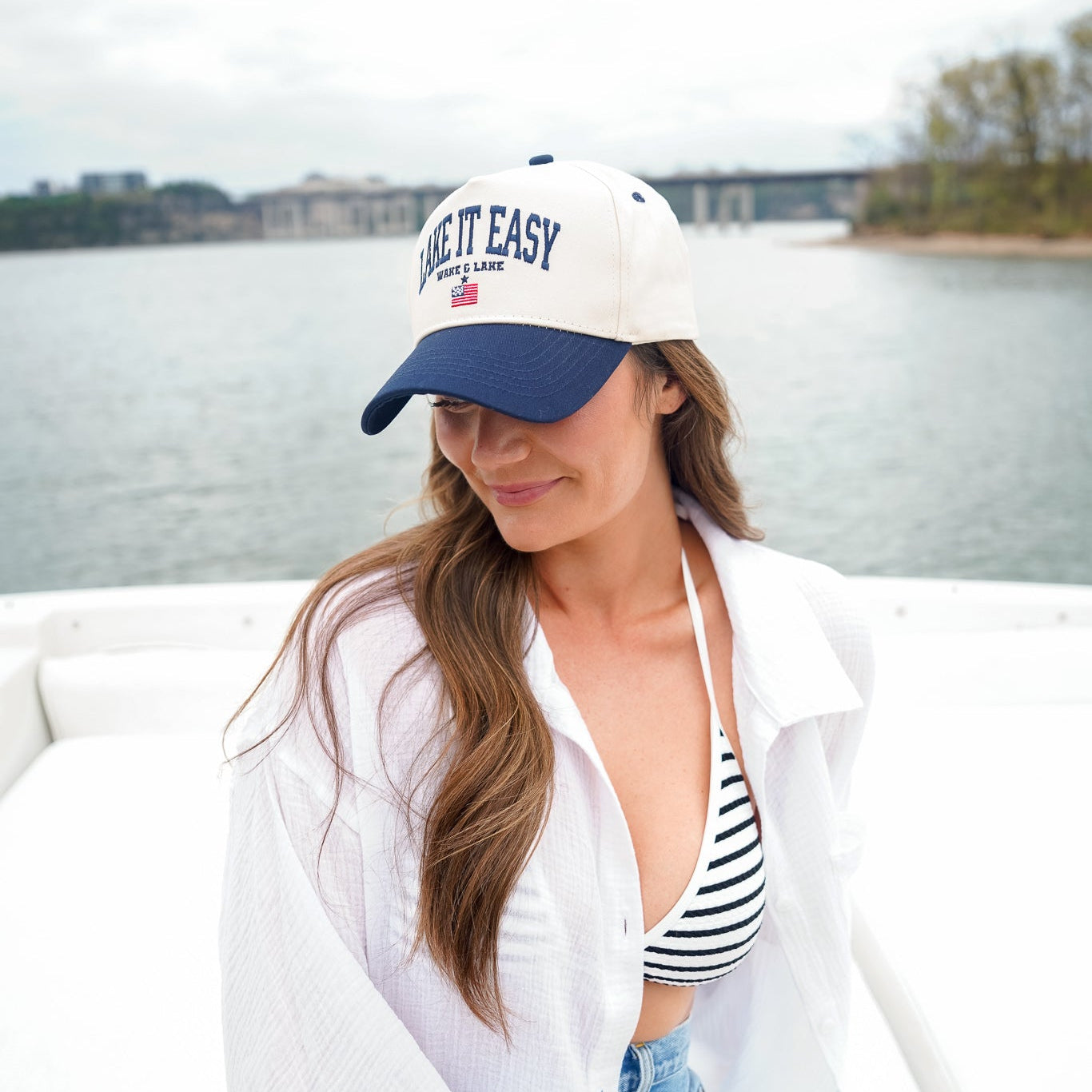 Woman wearing a 'Relax It Easy' cap by a body of water