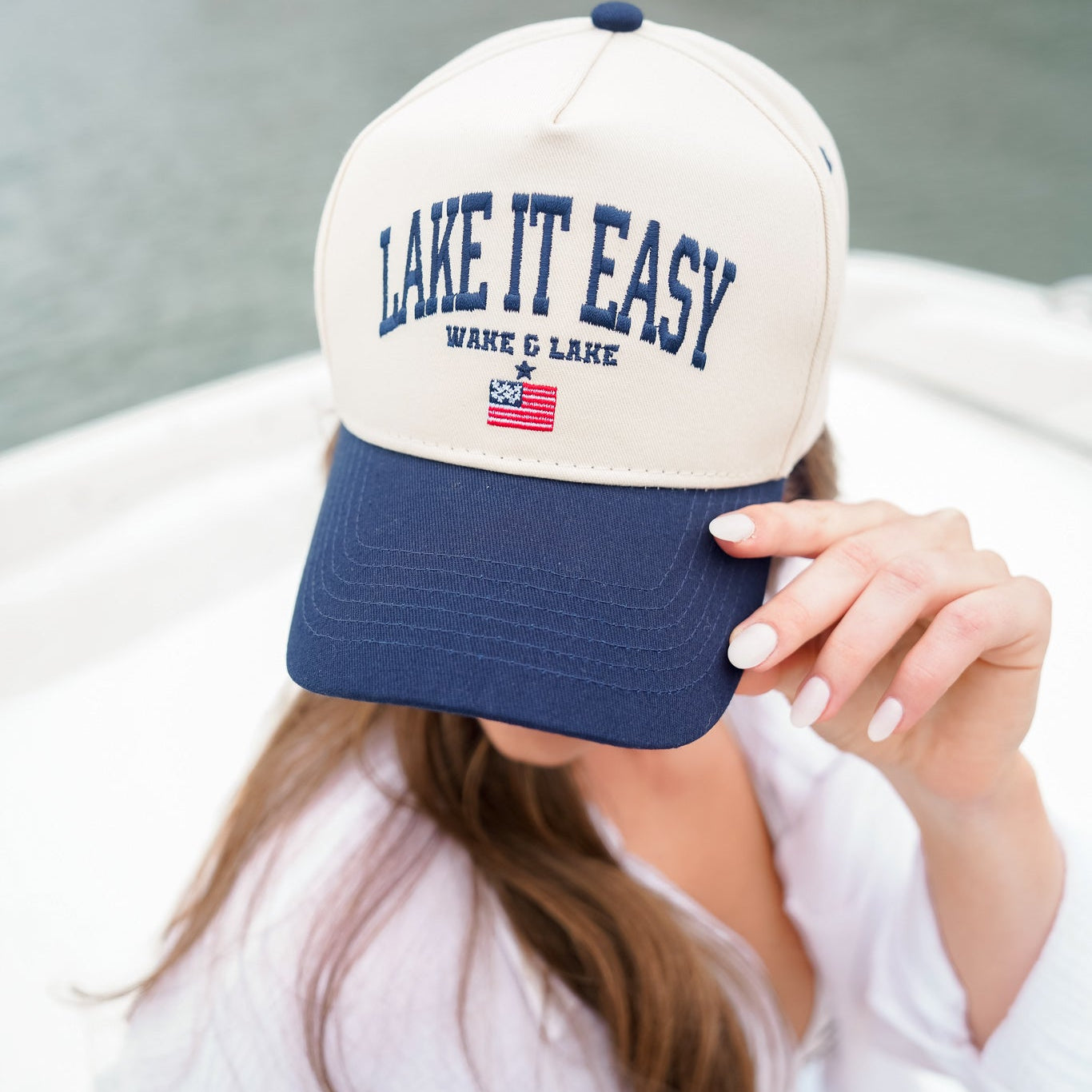 Person wearing a 'Lake It Easy' cap with a lake in the background