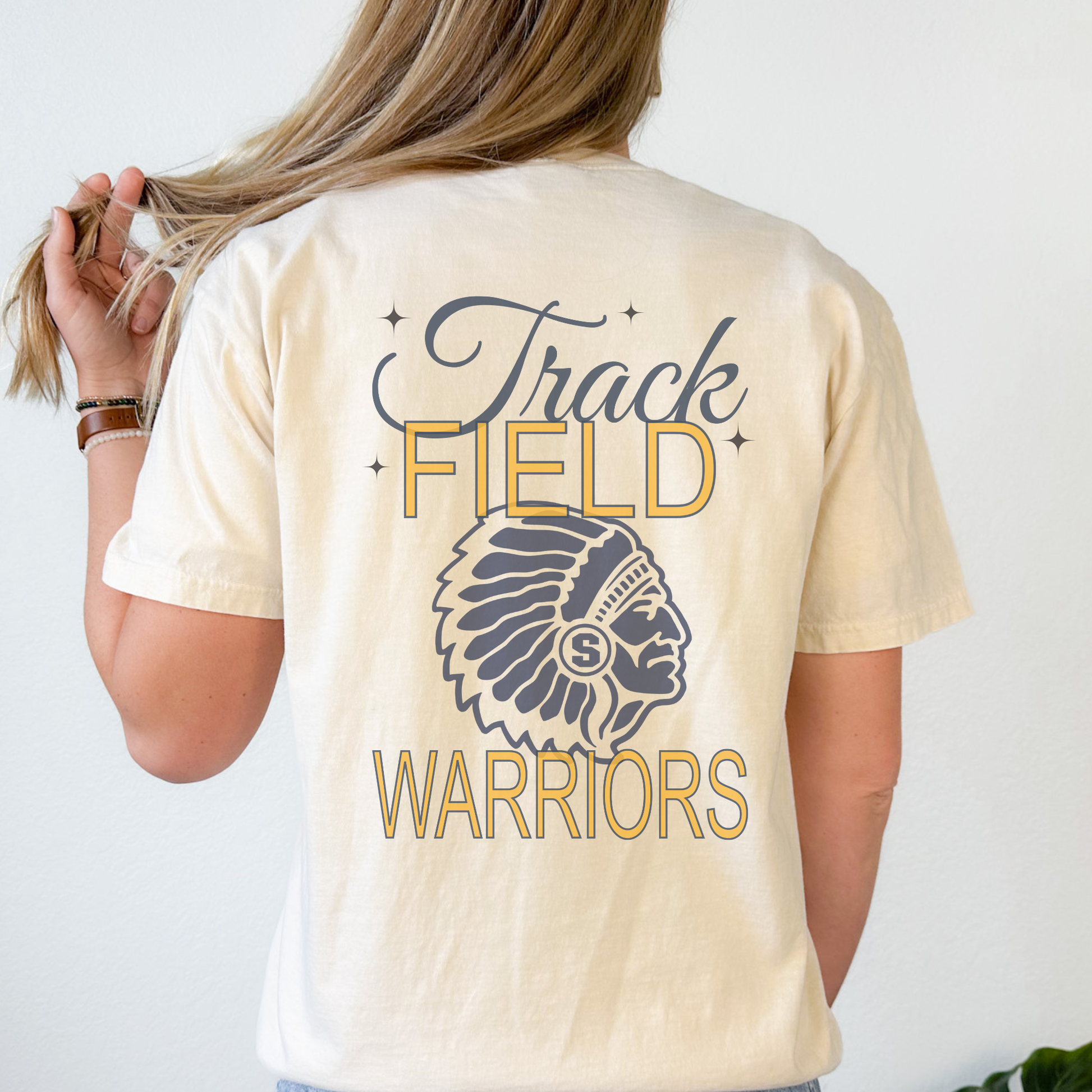 Person wearing a cream-colored t-shirt with 'Track Field Warriors' design on the back.