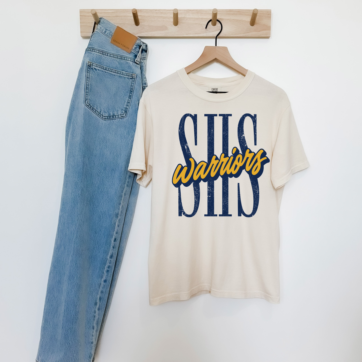 Ivory SHS Warriors graphic t-shirt with distressed navy SHS lettering and gold Warriors script, paired with light wash denim.