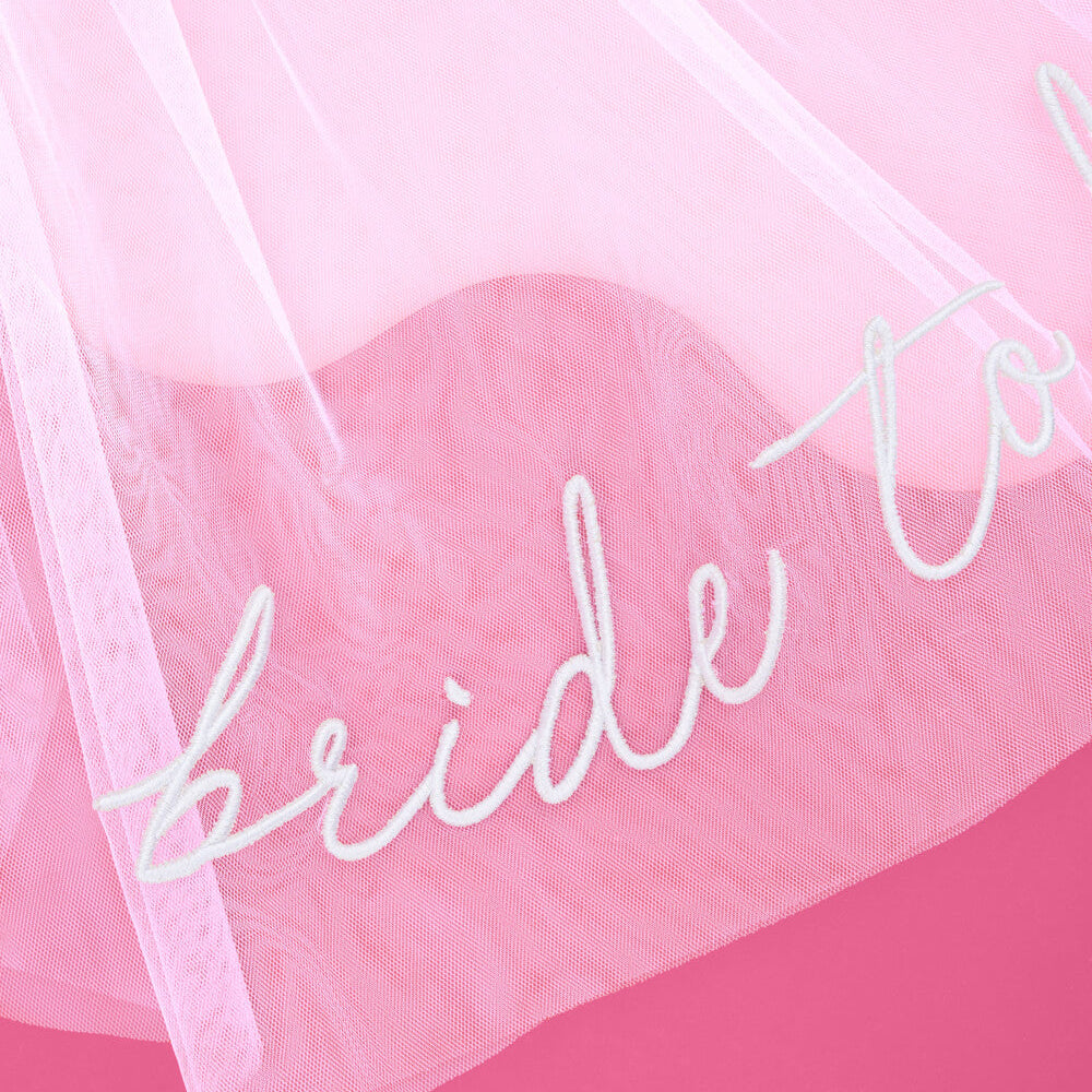 white 'bride to be' veil with white cursive text on a pink background