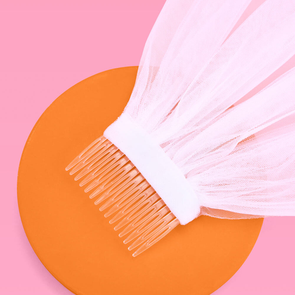 White hairbrush with clear bristles on an orange circle against a pink background