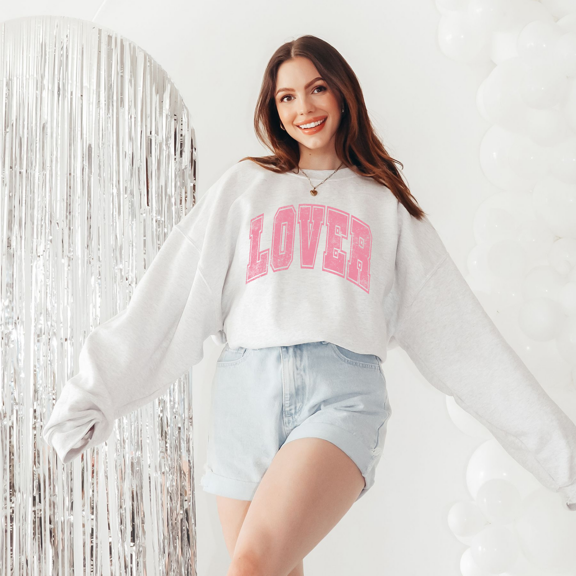 Lifestyle photo of LOVER crewneck styled with denim shorts and casual accessories