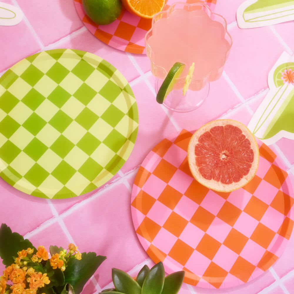 Colorful checkered plates with fruits on a pink tiled background