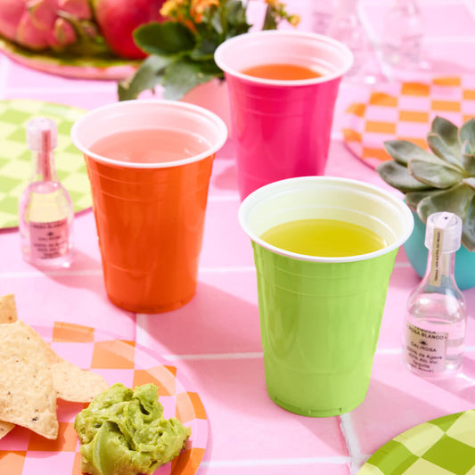 Colorful party setup with cups, snacks, and drinks on a checkered tablecloth.