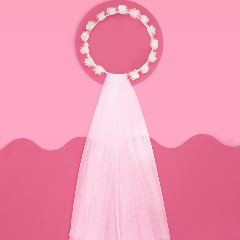 White wedding veil with a floral headpiece on a pink background