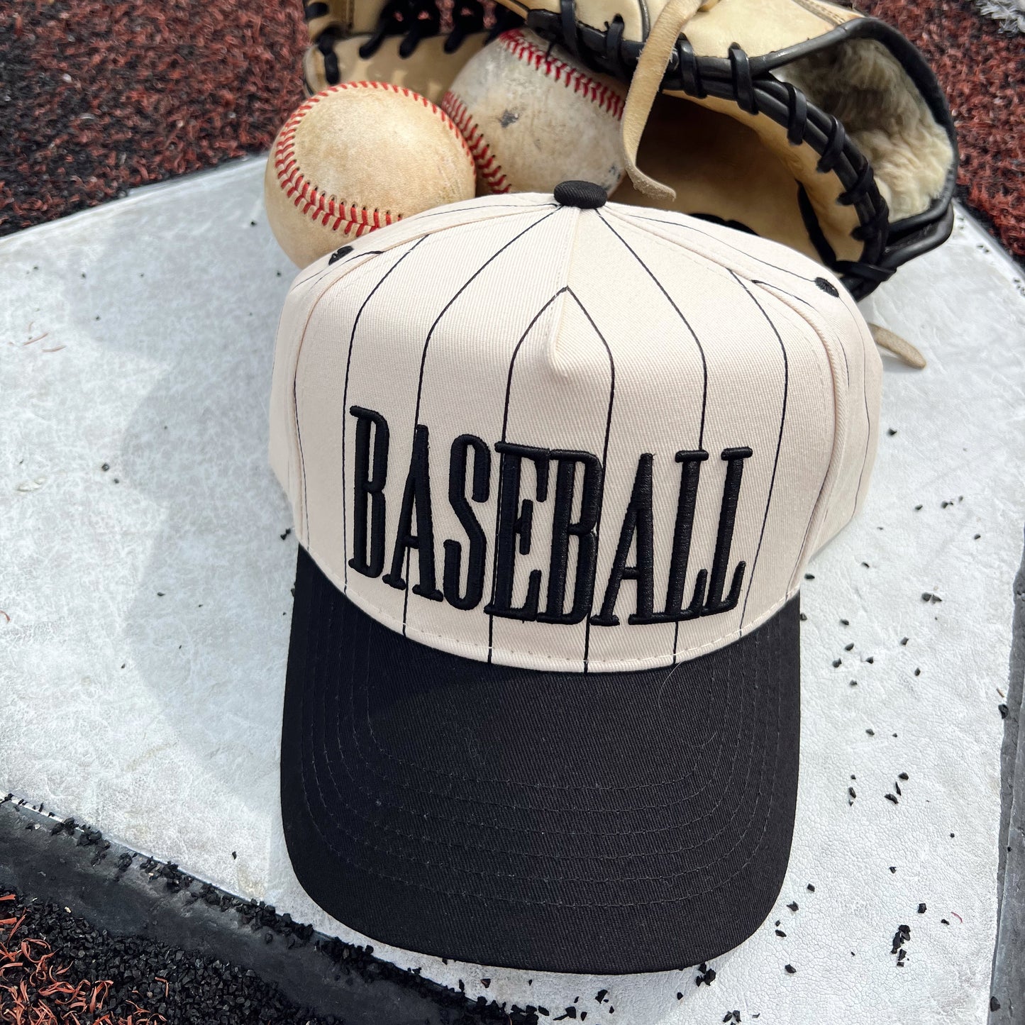 Baseball cap with 'BASEBALL' text, baseball, and glove on a baseball field