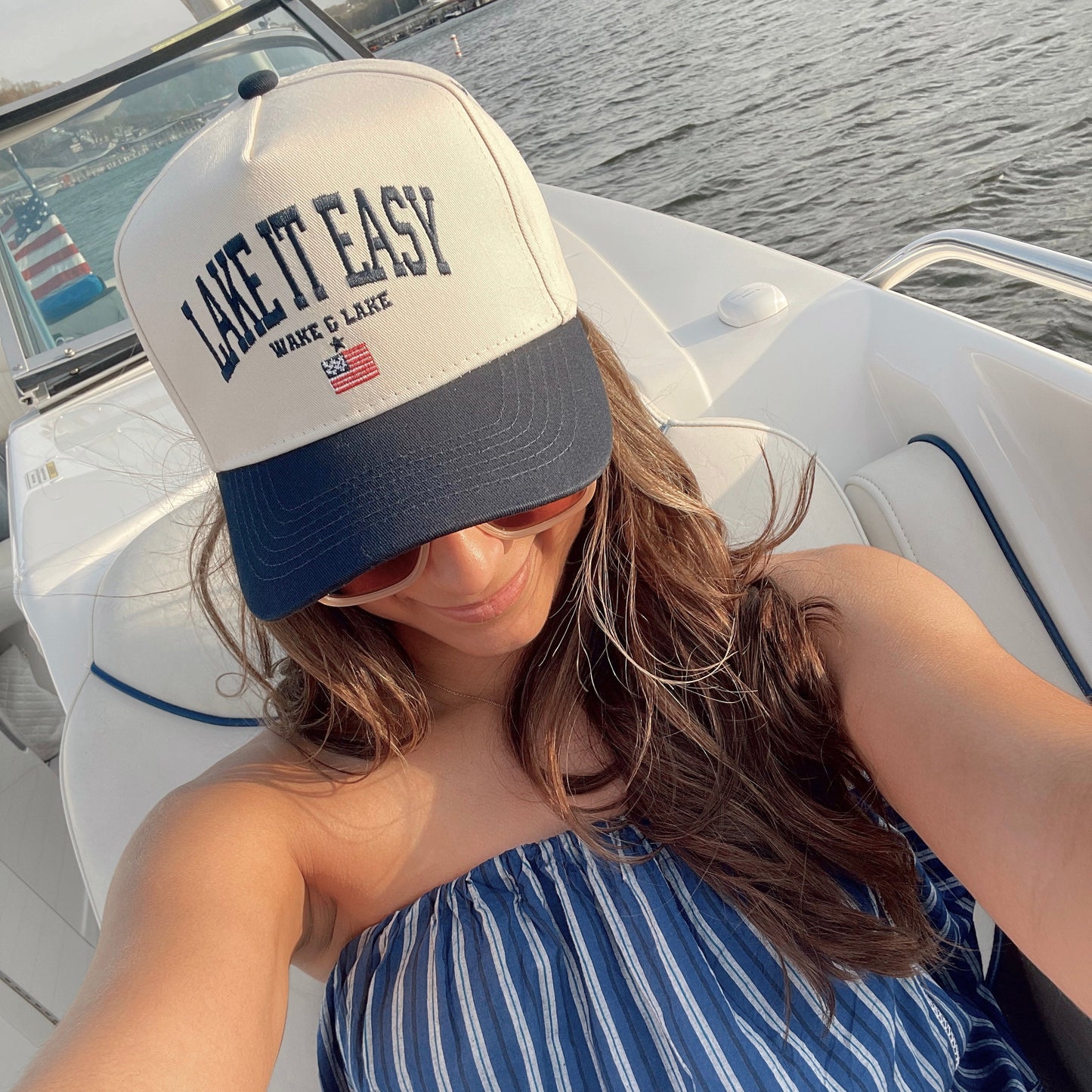 Woman wearing a 'Live It Easy' cap on a boat with water in the background