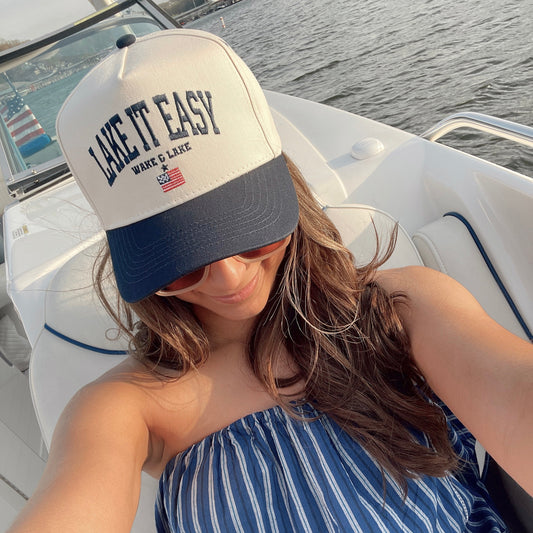 Woman wearing a 'Live It Easy' cap on a boat with water in the background