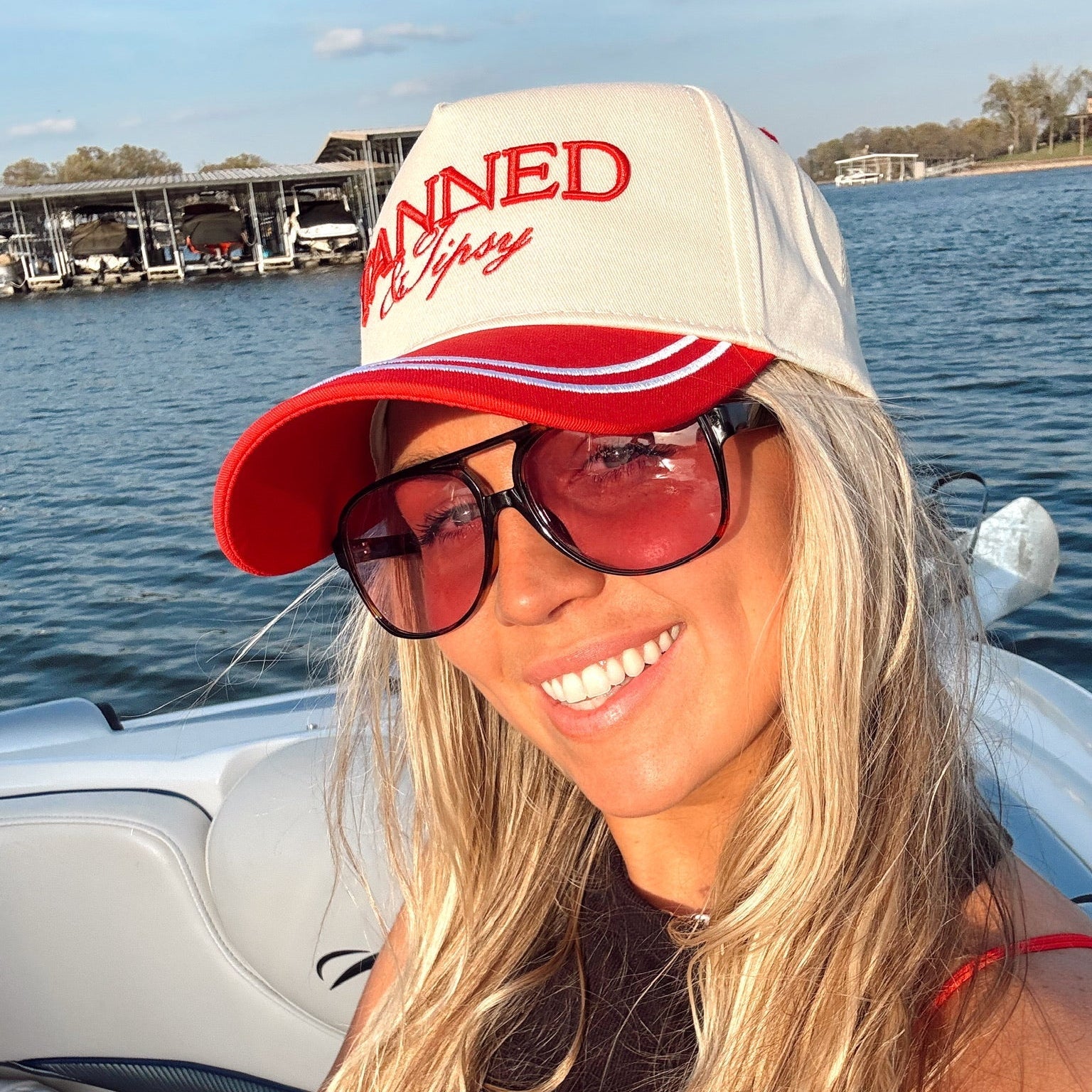 Woman wearing a cap with text on a boat by the water
