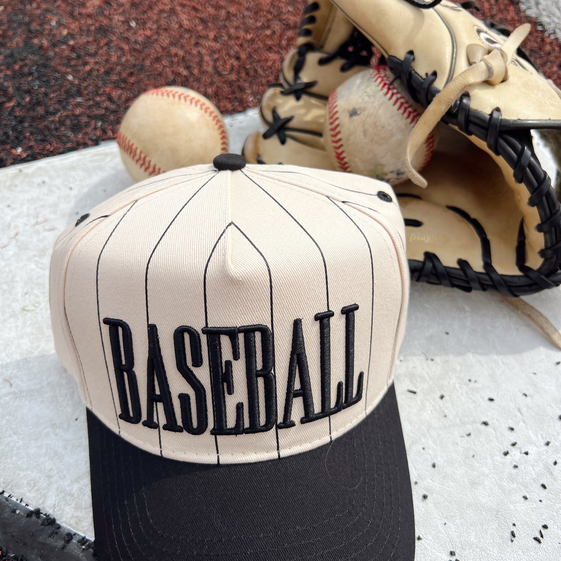 Baseball cap with 'BASEBALL' text, baseball, and glove on a textured surface