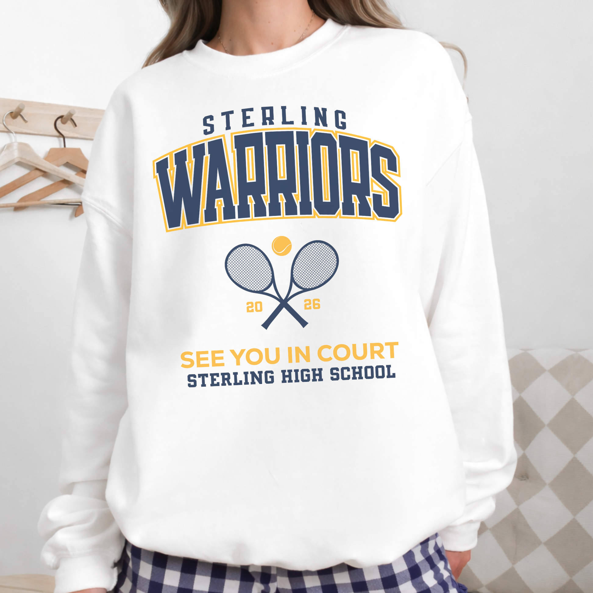 Woman wearing a white Sterling Warriors Tennis crewneck sweatshirt with “See You in Court” graphic