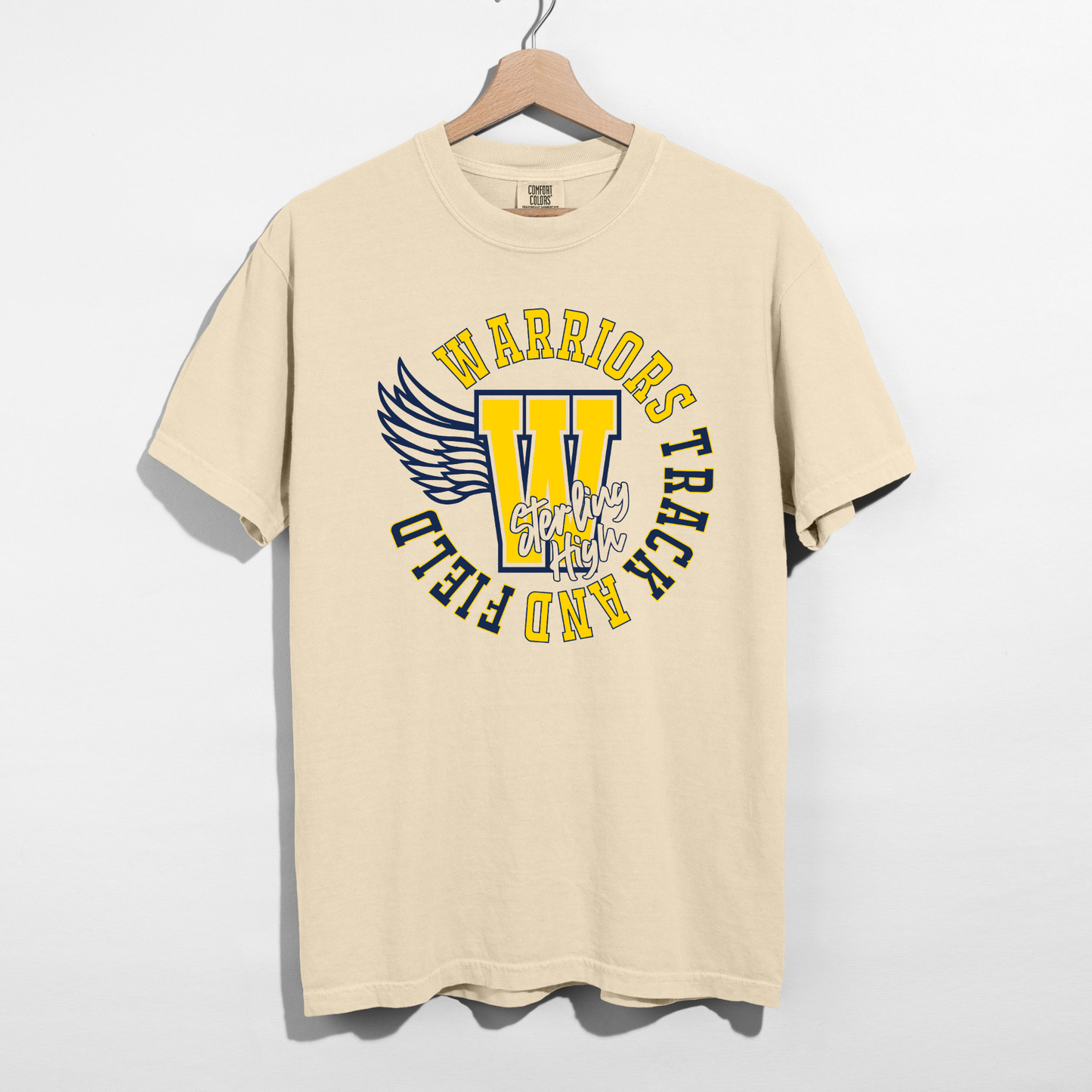 Beige t-shirt with 'Warriors' and 'Trick or Field' text on a hanger against a white background