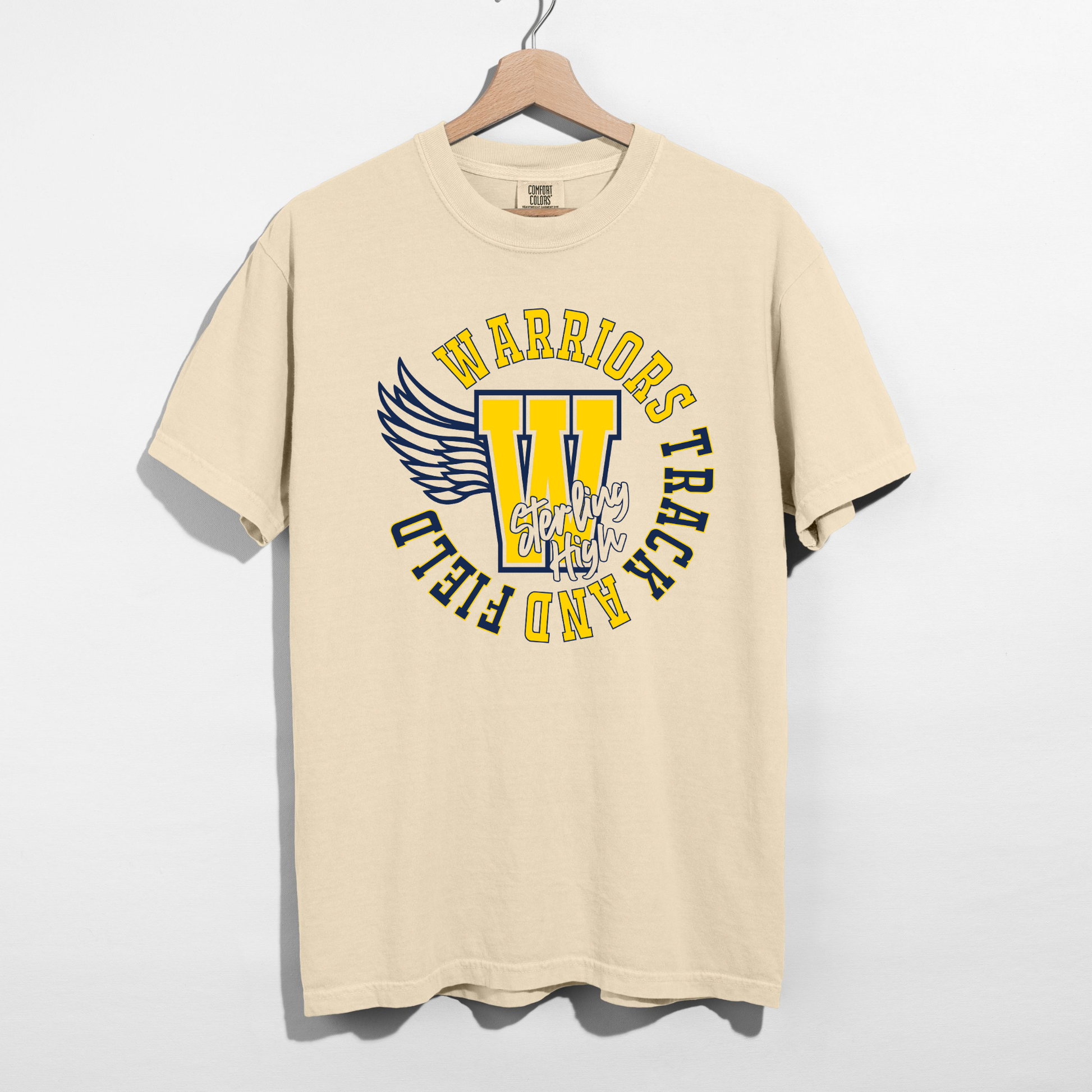 Beige t-shirt with 'Warriors' and 'Trick or Field' text on a hanger against a white background
