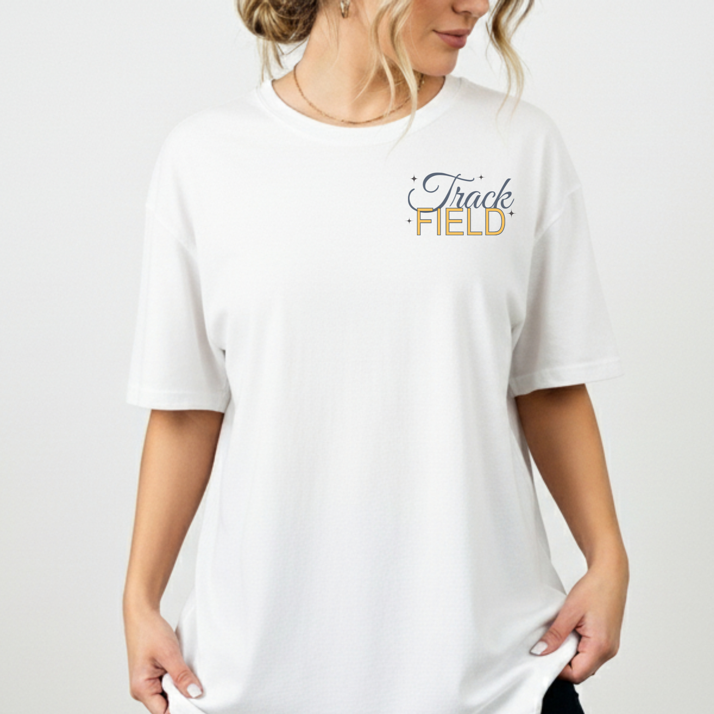 White t-shirt with 'Track Field' text worn by a person on a plain background