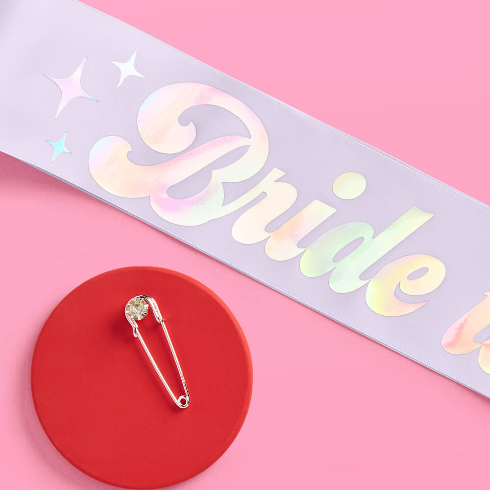 Holographic 'Bride to be' sash with a decorative brooch on a pink background