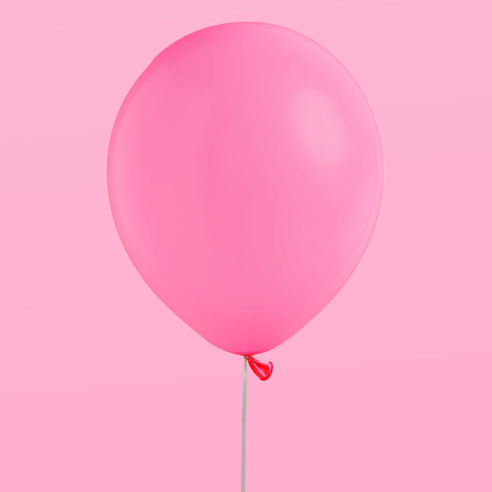 Single pink balloon against a pink background