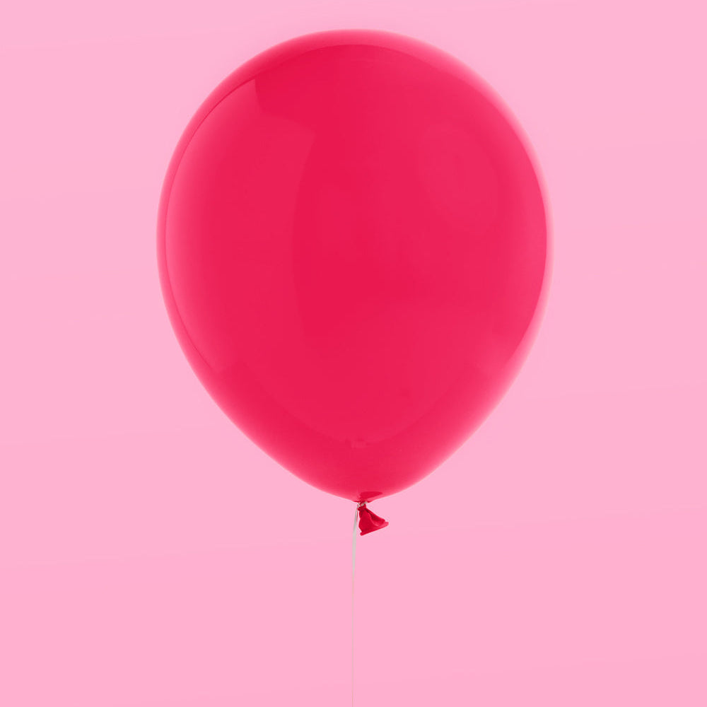 Single red balloon against a pink background